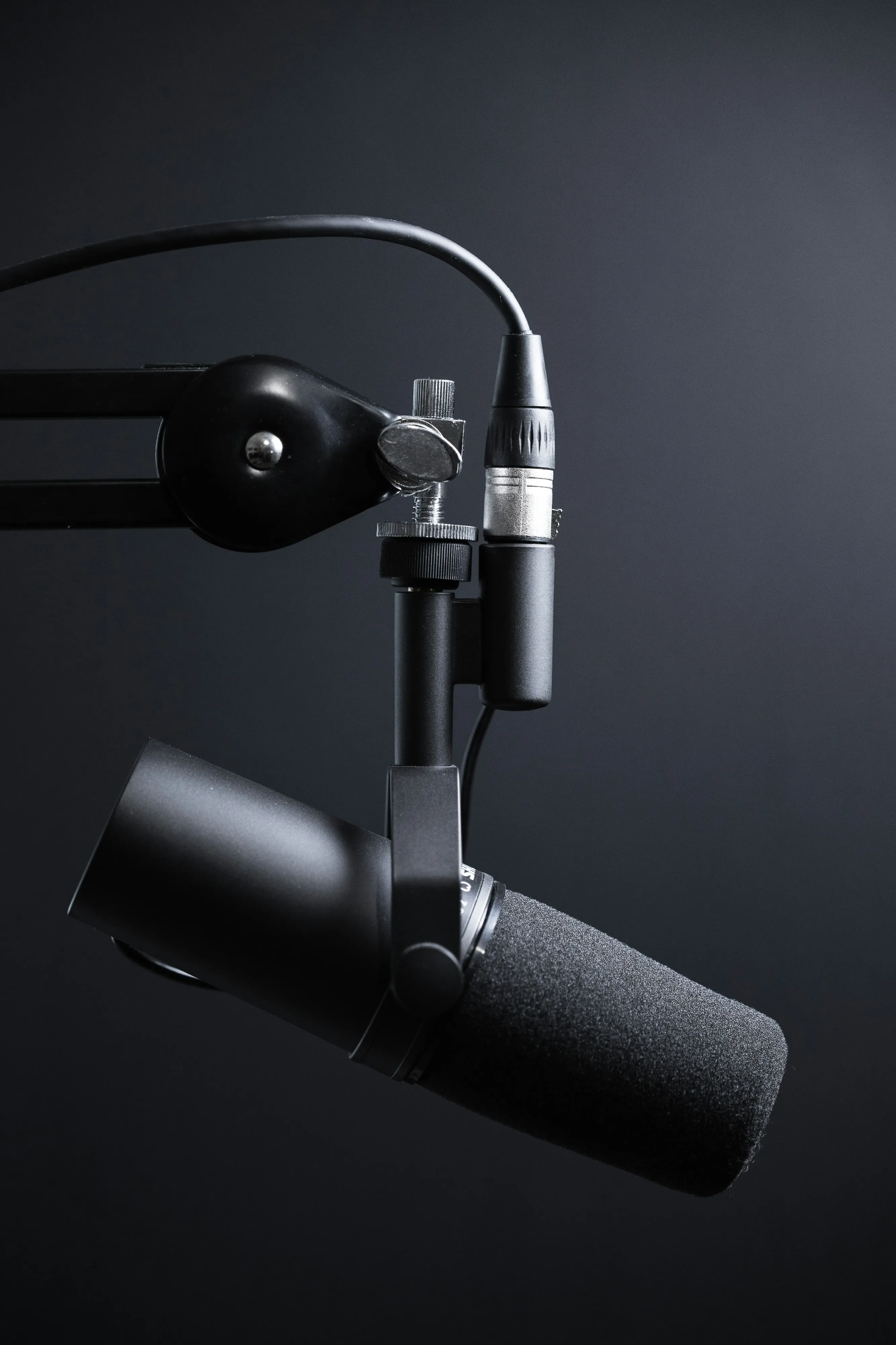 Minimalist podcast microphone with a vivid red cable against a near-black backdrop