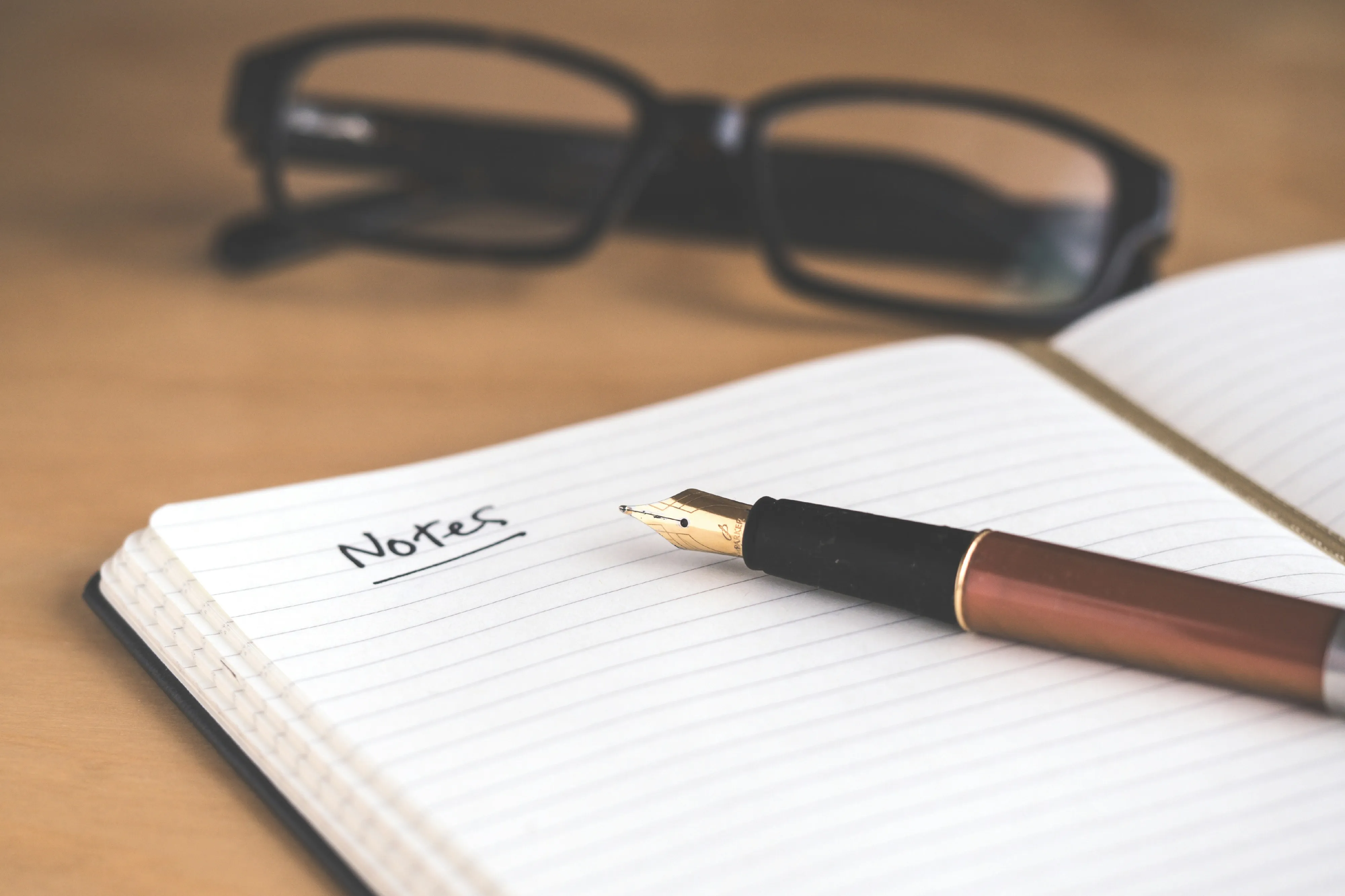 A closed notebook, soft window light, and a single red pencil